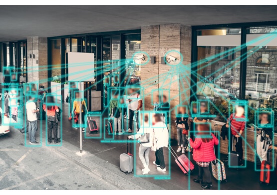 AI face-detection software identifying and tracking people with bounding boxes in CCTV footage of a public space